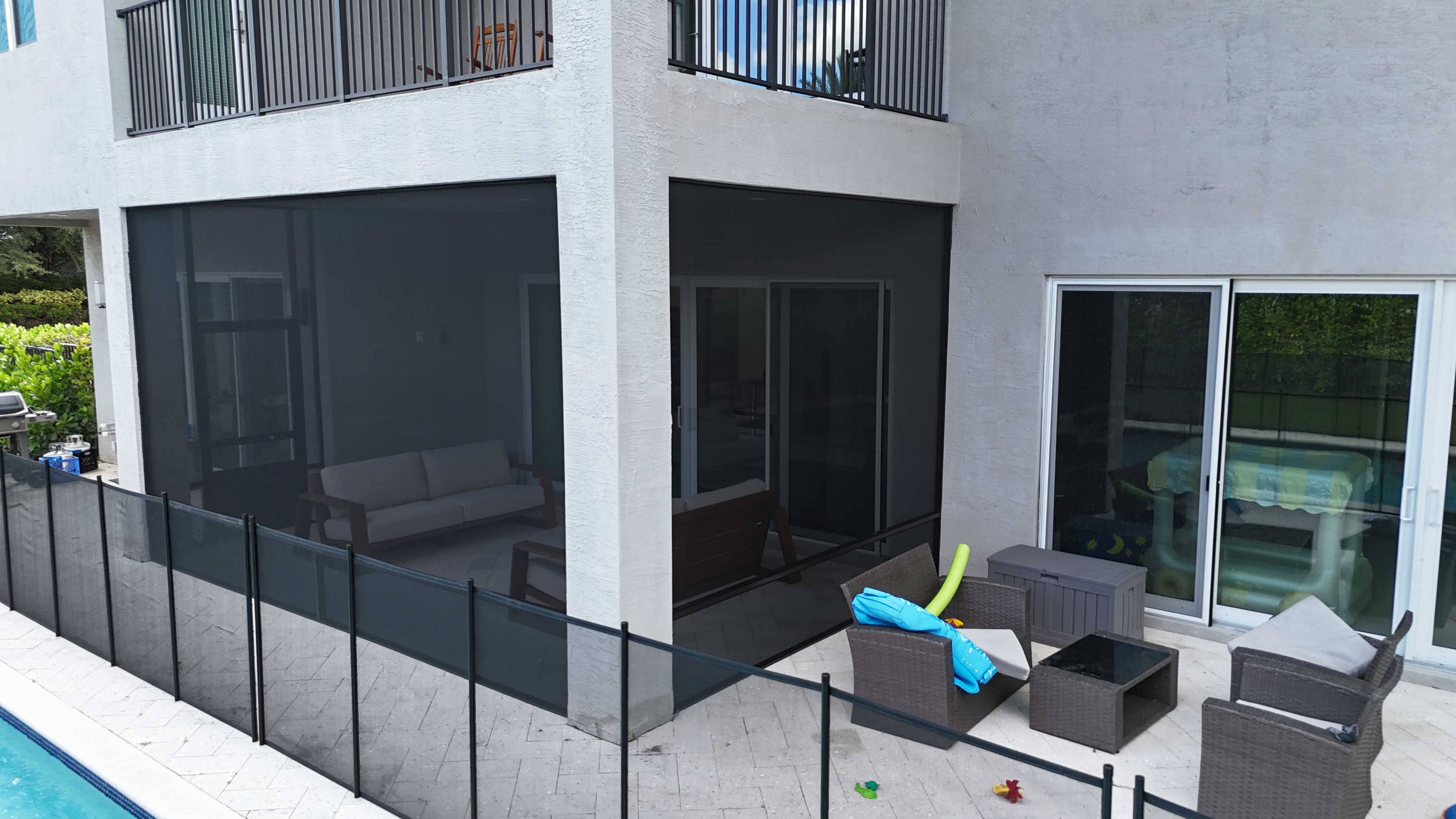 Modern pool screen enclosure at two-story contemporary home — dark frame panels