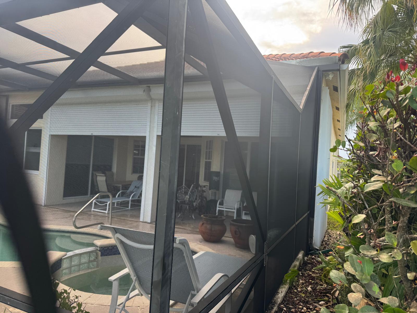 Close-up of pool screen enclosure corner — dark frame with pool visible through screens